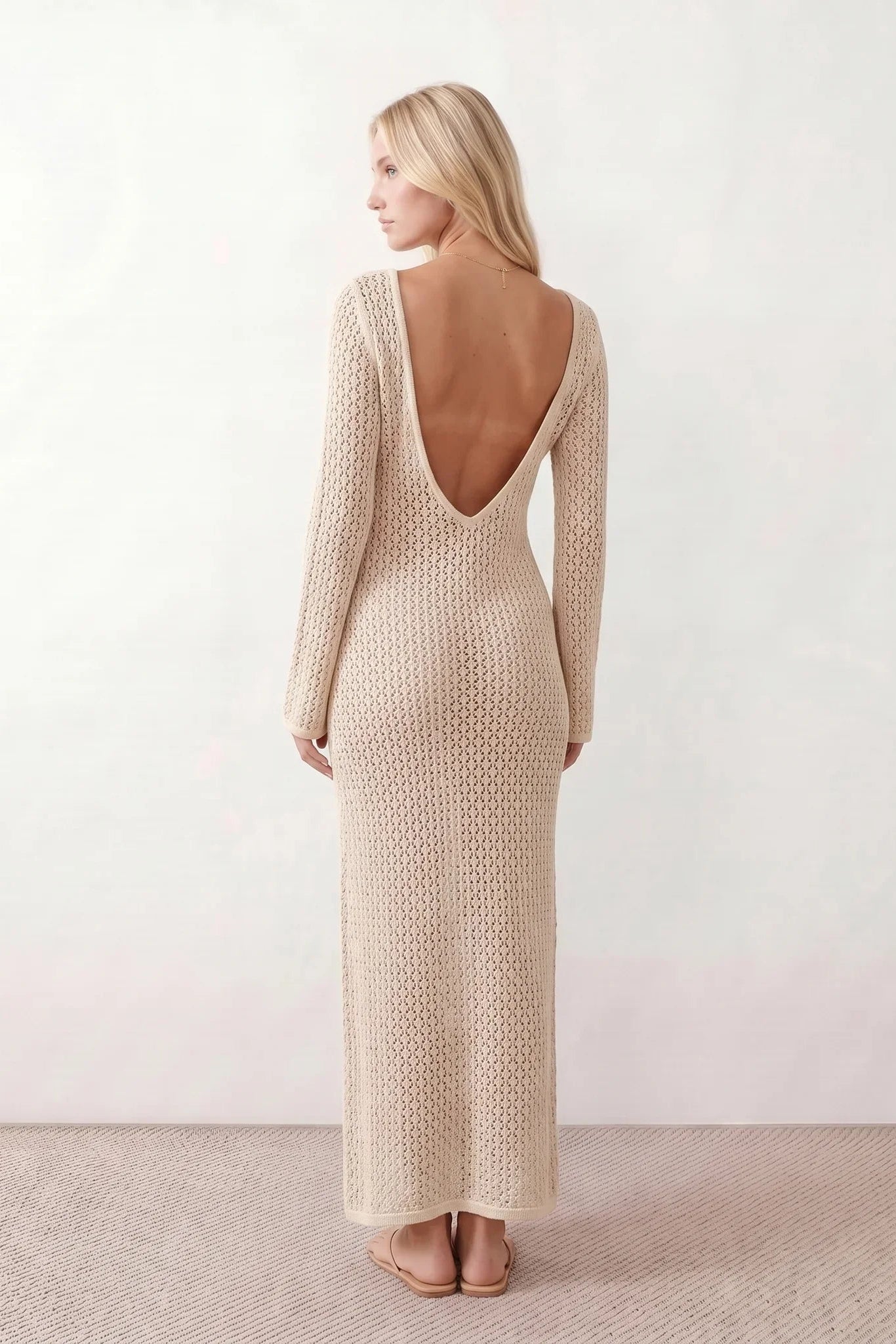 Woman wearing the Calixta Crochet Plunge Neck Maxi Dress in an elegant open-knit crochet design with a deep plunge V-neck, keyhole detail, long flared sleeves, low open back and fitted floor-length silhouette, ideal for beach holidays, festivals and summer occasion wear.