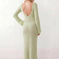 Woman wearing the Calixta Crochet Plunge Neck Maxi Dress in an elegant open-knit crochet design with a deep plunge V-neck, keyhole detail, long flared sleeves, low open back and fitted floor-length silhouette, ideal for beach holidays, festivals and summer occasion wear.