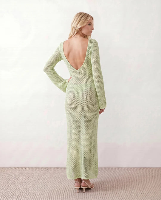 Woman wearing the Calixta Crochet Plunge Neck Maxi Dress in an elegant open-knit crochet design with a deep plunge V-neck, keyhole detail, long flared sleeves, low open back and fitted floor-length silhouette, ideal for beach holidays, festivals and summer occasion wear.