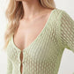 Woman wearing the Calixta Crochet Plunge Neck Maxi Dress in an elegant open-knit crochet design with a deep plunge V-neck, keyhole detail, long flared sleeves, low open back and fitted floor-length silhouette, ideal for beach holidays, festivals and summer occasion wear.