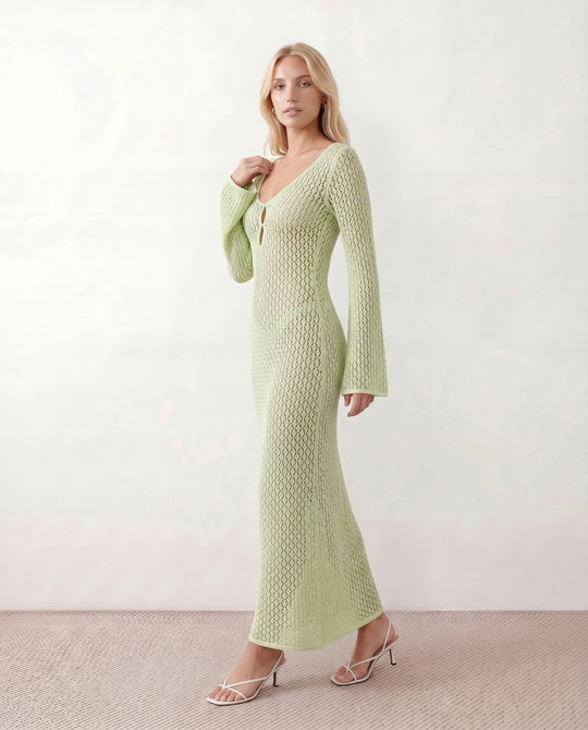 Woman wearing the Calixta Crochet Plunge Neck Maxi Dress in an elegant open-knit crochet design with a deep plunge V-neck, keyhole detail, long flared sleeves, low open back and fitted floor-length silhouette, ideal for beach holidays, festivals and summer occasion wear.