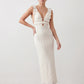 Woman wearing the crochet mermaid maxi dress featuring an intricate crochet knit, plunging V-neckline, ruffled shoulder straps, keyhole waist cut-out, adjustable lace-up open back, scalloped hem, and a figure-hugging maxi silhouette, ideal for weddings, cocktail parties, and elegant evening occasions.