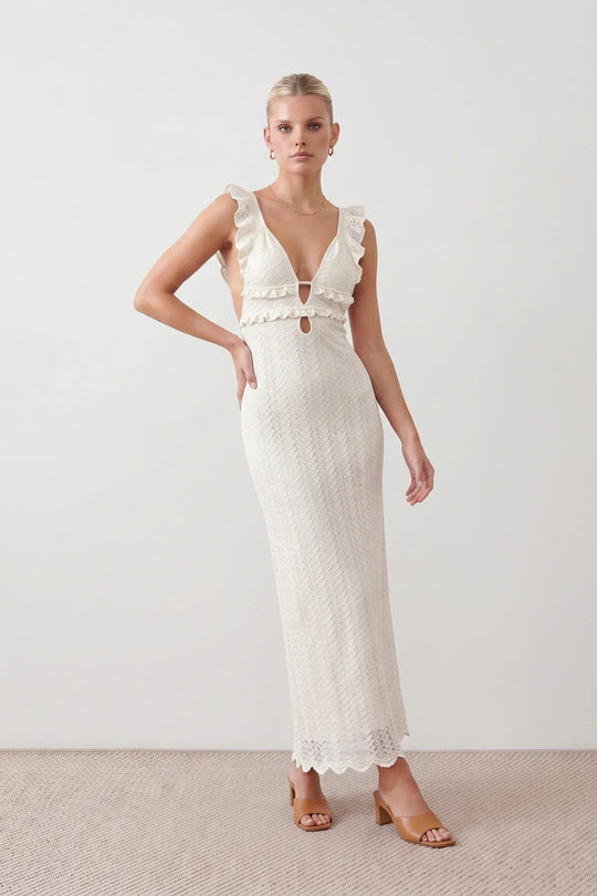 Woman wearing the crochet mermaid maxi dress featuring an intricate crochet knit, plunging V-neckline, ruffled shoulder straps, keyhole waist cut-out, adjustable lace-up open back, scalloped hem, and a figure-hugging maxi silhouette, ideal for weddings, cocktail parties, and elegant evening occasions.