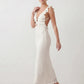 Woman wearing the crochet mermaid maxi dress featuring an intricate crochet knit, plunging V-neckline, ruffled shoulder straps, keyhole waist cut-out, adjustable lace-up open back, scalloped hem, and a figure-hugging maxi silhouette, ideal for weddings, cocktail parties, and elegant evening occasions.