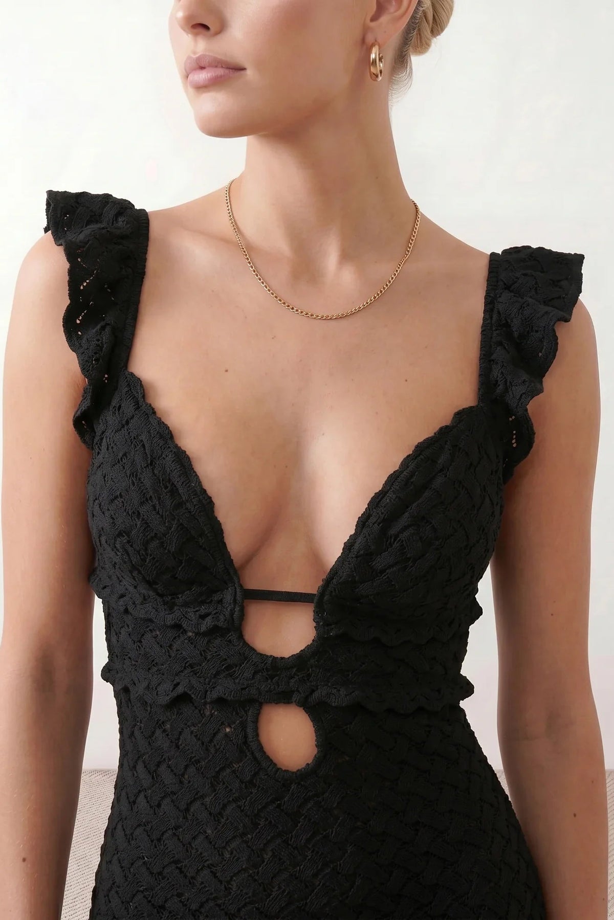 Woman wearing the crochet mermaid maxi dress featuring an intricate crochet knit, plunging V-neckline, ruffled shoulder straps, keyhole waist cut-out, adjustable lace-up open back, scalloped hem, and a figure-hugging maxi silhouette, ideal for weddings, cocktail parties, and elegant evening occasions.