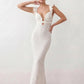 Woman wearing the Raluca crochet mermaid maxi dress featuring an intricate crochet knit, plunging V-neckline, ruffled shoulder straps, keyhole waist cut-out, adjustable lace-up open back, scalloped hem, and a figure-hugging maxi silhouette, ideal for weddings, cocktail parties, and elegant evening occasions.