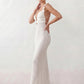 Woman wearing the crochet mermaid maxi dress featuring an intricate crochet knit, plunging V-neckline, ruffled shoulder straps, keyhole waist cut-out, adjustable lace-up open back, scalloped hem, and a figure-hugging maxi silhouette, ideal for weddings, cocktail parties, and elegant evening occasions.
