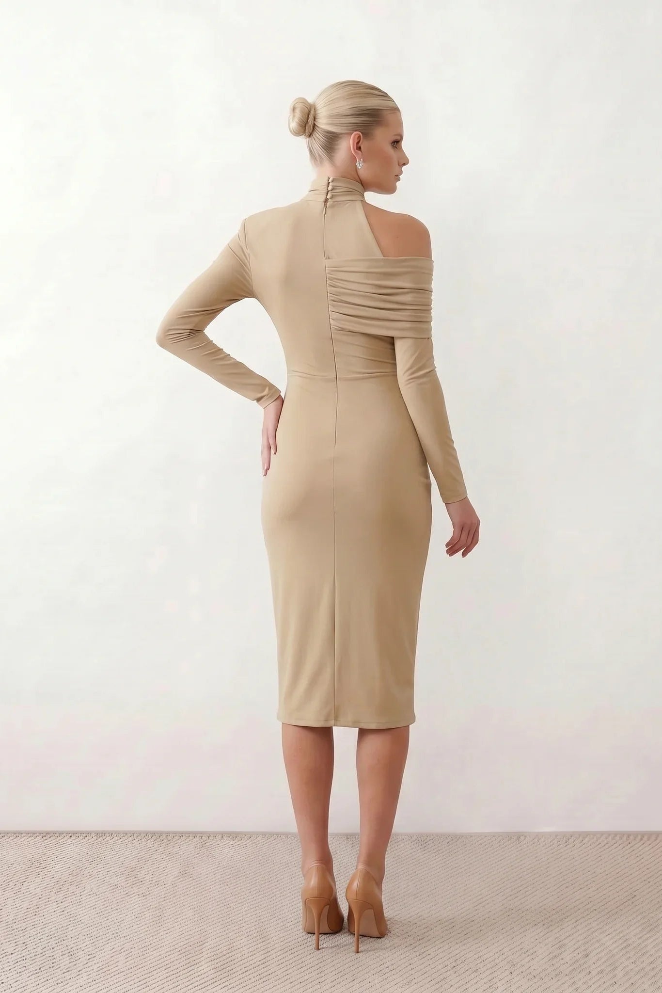 Woman wearing the Asymmetric Neck Open Back Midi Dress featuring an asymmetric mock-neck halter, off-shoulder ruched detailing, long fitted sleeves, an elegant open back, fitted midi silhouette and front slit, styled for weddings, cocktail parties and formal occasions.