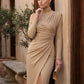Woman wearing the Asymmetric Neck Open Back Midi Dress featuring an asymmetric mock-neck halter, off-shoulder ruched detailing, long fitted sleeves, an elegant open back, fitted midi silhouette and front slit, styled for weddings, cocktail parties and formal occasions.