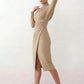 Woman wearing the Asymmetric Neck Open Back Midi Dress featuring an asymmetric mock-neck halter, off-shoulder ruched detailing, long fitted sleeves, an elegant open back, fitted midi silhouette and front slit, styled for weddings, cocktail parties and formal occasions.
