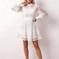 Woman wearing the Lace Openwork Mini Dress featuring intricate lace-inspired openwork, a mandarin collar, decorative front buttons, long sleeves, a fitted waist, and a scalloped mini hem, ideal for weddings, cocktail parties, and elegant occasions.