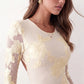 Woman wearing the Anahera open back fitted mini dress with sheer embroidered long sleeves, a round neckline, side cut-out details, and a sleek sheath silhouette, ideal for cocktail parties and evening occasions.