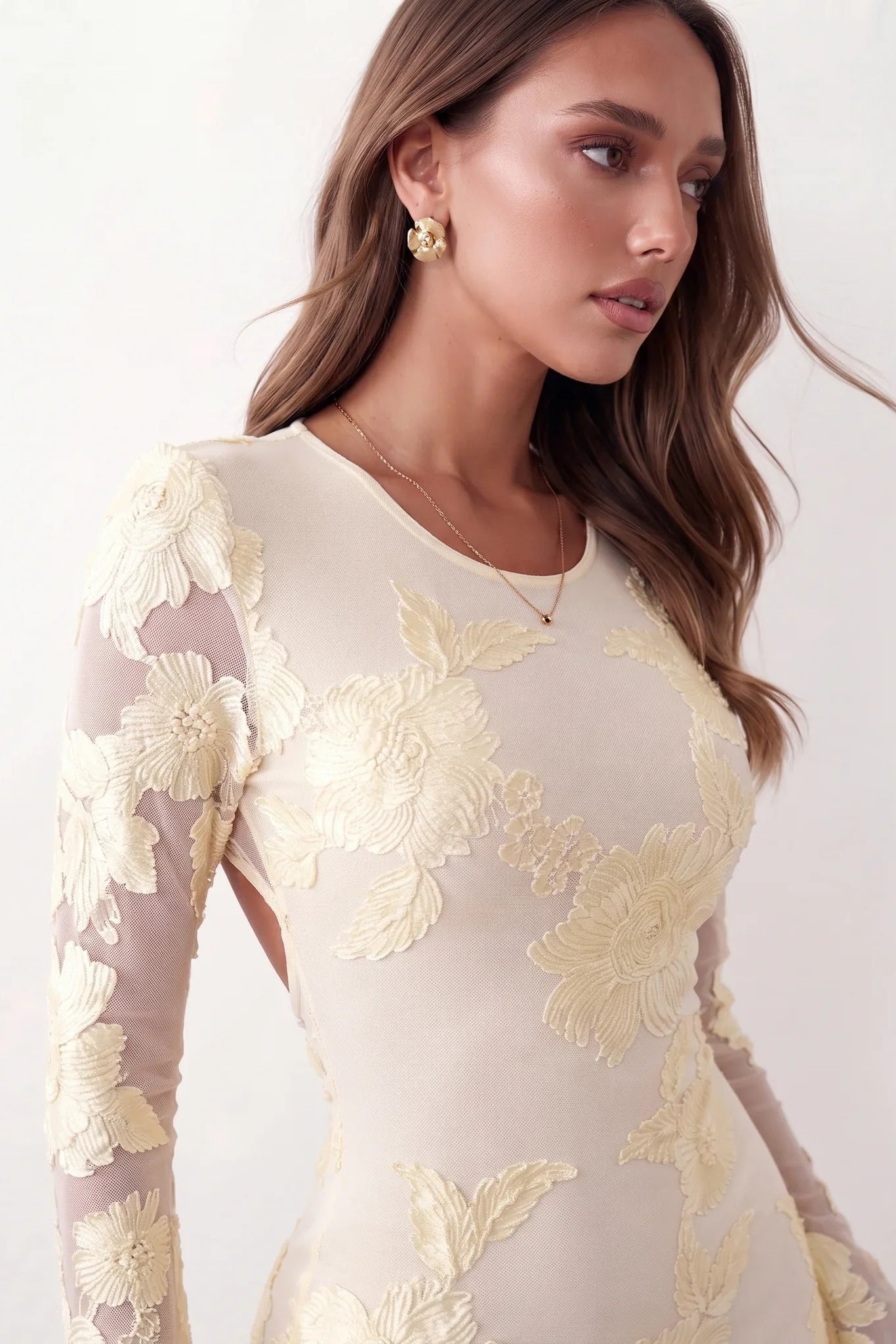 Woman wearing the Anahera open back fitted mini dress with sheer embroidered long sleeves, a round neckline, side cut-out details, and a sleek sheath silhouette, ideal for cocktail parties and evening occasions.
