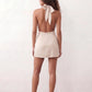 Woman wearing the Glossy Halter Mini Dress in a lustrous glossy finish, featuring a draped cowl halter neckline, open back with adjustable tie closure, side cut-out, ruched waist, and an A-line mini skirt, ideal for parties and evening occasions.