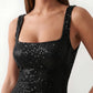 Woman wearing the Mihaela sequined low back maxi dress featuring allover sequin mesh, a square neckline, wide shoulder straps, a low open back, and a fitted floor-length sheath silhouette.