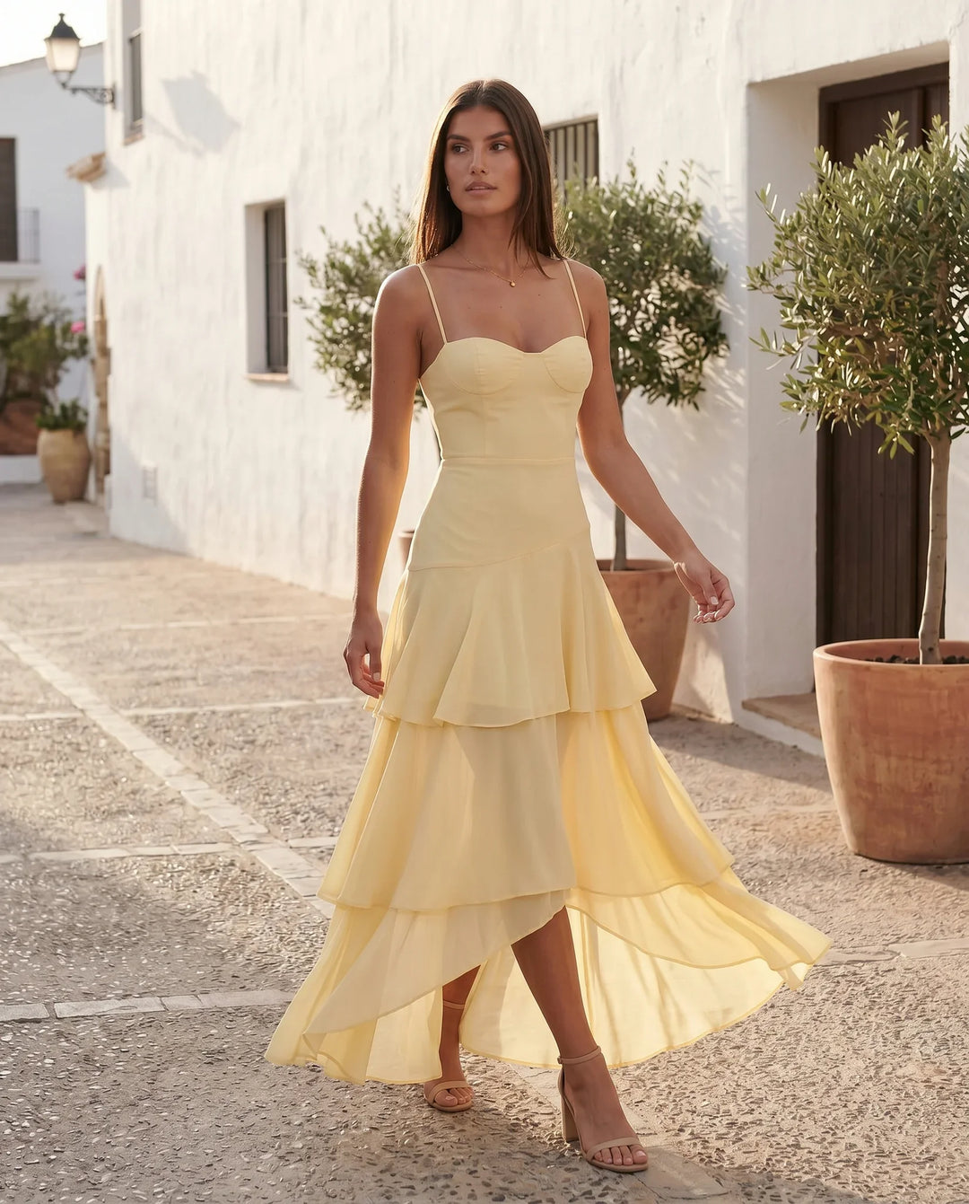 Elsie spaghetti strap sweetheart maxi dress with a structured corset bodice, delicate spaghetti straps, sheer panel detailing, an asymmetric three-tier chiffon skirt with ruffle hem, front slit, and a flowing high-low silhouette, perfect for weddings and special occasions.