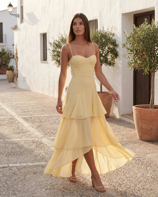 Elsie spaghetti strap sweetheart maxi dress with a structured corset bodice, delicate spaghetti straps, sheer panel detailing, an asymmetric three-tier chiffon skirt with ruffle hem, front slit, and a flowing high-low silhouette, perfect for weddings and special occasions.