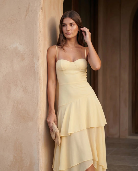 Elsie spaghetti strap sweetheart maxi dress with a structured corset bodice, delicate spaghetti straps, sheer panel detailing, an asymmetric three-tier chiffon skirt with ruffle hem, front slit, and a flowing high-low silhouette, perfect for weddings and special occasions.
