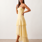 Elsie spaghetti strap sweetheart maxi dress with a structured corset bodice, delicate spaghetti straps, sheer panel detailing, an asymmetric three-tier chiffon skirt with ruffle hem, front slit, and a flowing high-low silhouette, perfect for weddings and special occasions.