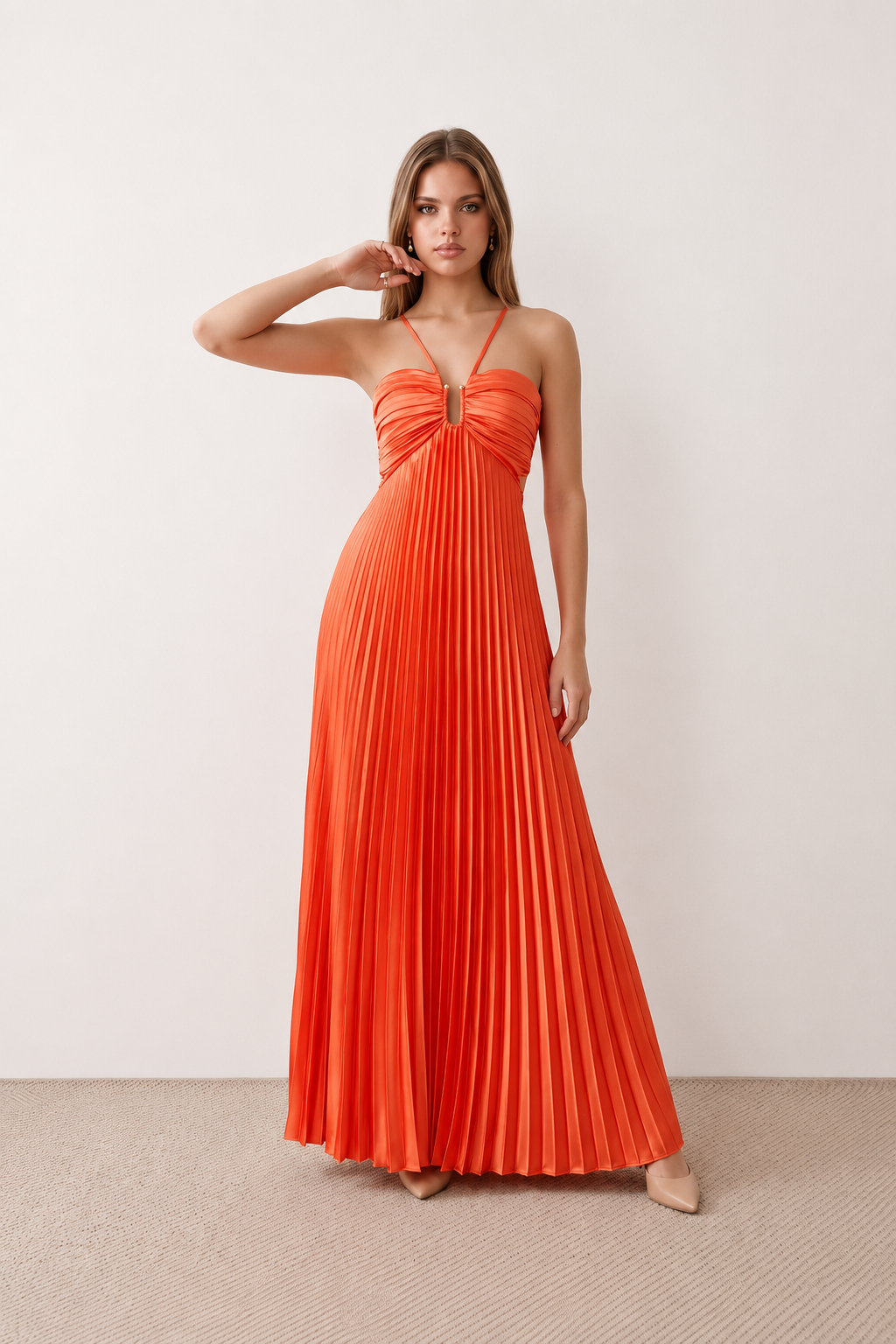 Woman wearing the Estella strapless pleated maxi dress featuring a ruched empire bodice, keyhole hardware detail, side cutout, open back with tie closure, and a flowing accordion-pleated floor-length skirt.