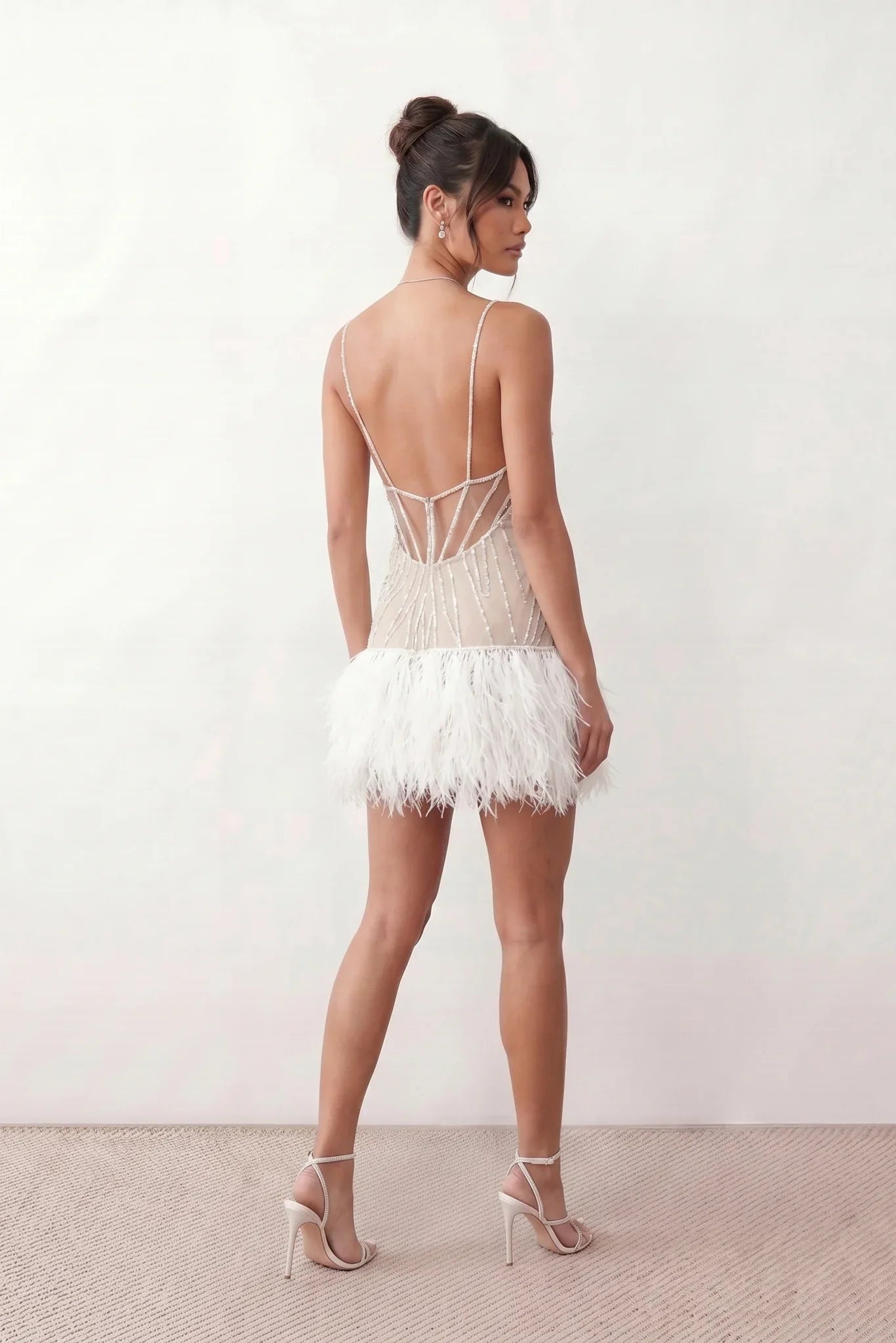 Mariela sequined spaghetti strap mini dress with a sheer sequined bodice, open low back featuring beaded cage straps, layered ostrich feather trim, and a straight-cut mini silhouette for cocktail parties and evening events.