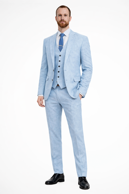 Man wearing a light blue suit with a white shirt and black shoes on a white background