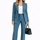 Woman wearing a blue suit with a white top and holding a black handbag on a white background