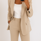 Person wearing a beige suit holding a smartphone on a white background