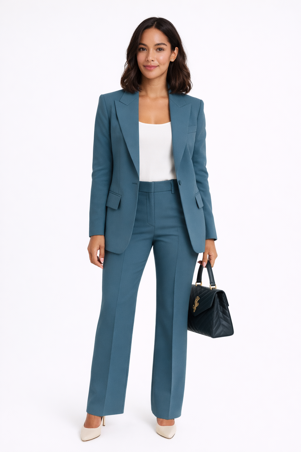 Woman wearing a teal suit with a white top and holding a black handbag on a white background