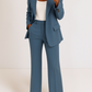 Person wearing a blue suit with a white top on a plain background