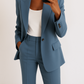 Person wearing a blue suit with a white top against a plain background