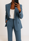 Person wearing a blue suit with a white top against a plain background