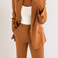 Person wearing a brown suit with a white top on a plain background