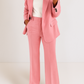 Person wearing a pink suit with a white top on a plain background