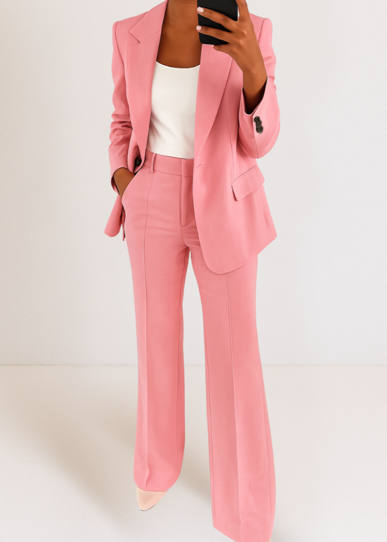 Person wearing a pink suit with a white top on a plain background