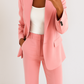 Person wearing a pink suit with a white top against a light background