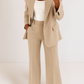 Person wearing a beige suit with a white top on a plain background