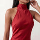 Woman wearing the Winnie satin halter maxi dress featuring a glossy satin finish, halter neckline with tie-back detail, open draped back, and a floor-length relaxed silhouette.