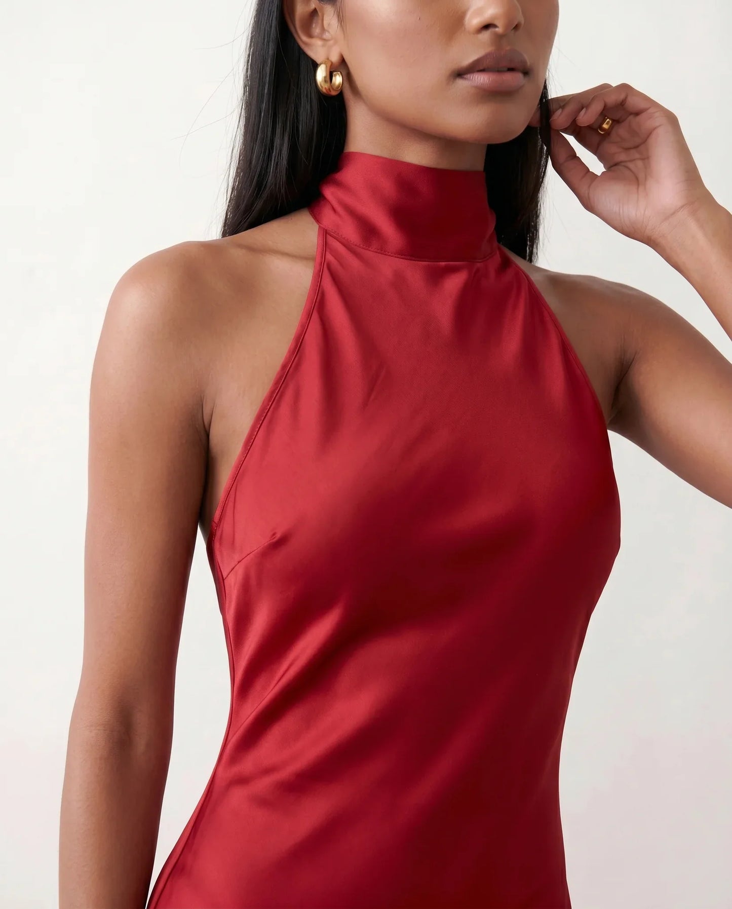 Woman wearing the Winnie satin halter maxi dress featuring a glossy satin finish, halter neckline with tie-back detail, open draped back, and a floor-length relaxed silhouette.