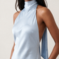 Woman wearing the Winnie satin halter maxi dress featuring a glossy satin finish, halter neckline with tie-back detail, open draped back, and a floor-length relaxed silhouette.