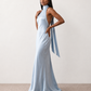 Woman wearing the Winnie satin halter maxi dress featuring a glossy satin finish, halter neckline with tie-back detail, open draped back, and a floor-length relaxed silhouette.
