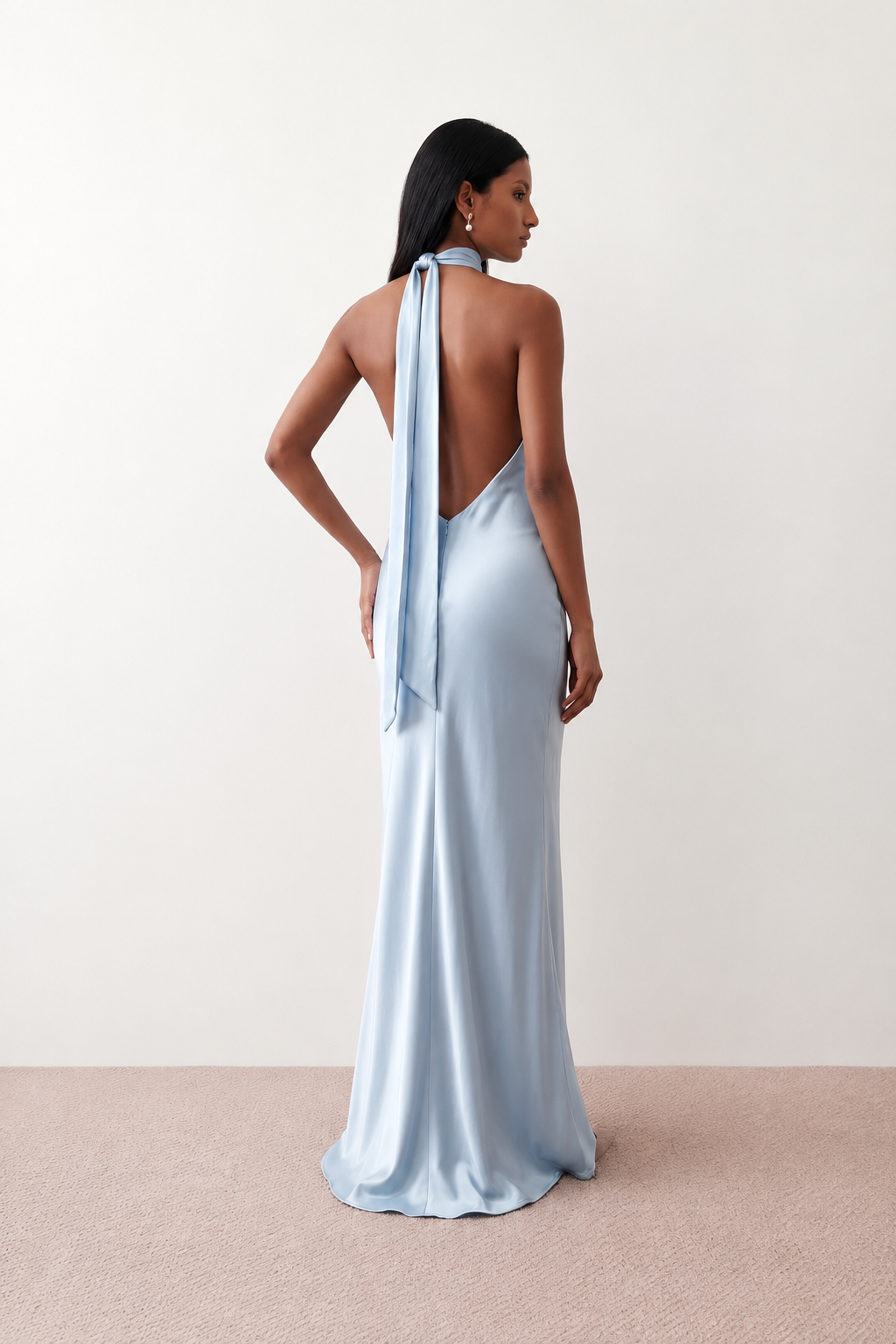 Woman wearing the Winnie satin halter maxi dress featuring a glossy satin finish, halter neckline with tie-back detail, open draped back, and a floor-length relaxed silhouette.