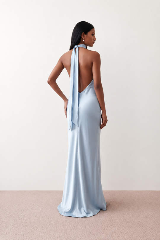 Woman wearing the Winnie satin halter maxi dress featuring a glossy satin finish, halter neckline with tie-back detail, open draped back, and a floor-length relaxed silhouette.