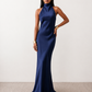 Woman wearing the Winnie satin halter maxi dress featuring a glossy satin finish, halter neckline with tie-back detail, open draped back, and a floor-length relaxed silhouette.