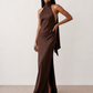 Woman wearing the Winnie satin halter maxi dress featuring a glossy satin finish, halter neckline with tie-back detail, open draped back, and a floor-length relaxed silhouette.