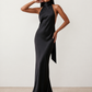 Woman wearing the Winnie satin halter maxi dress featuring a glossy satin finish, halter neckline with tie-back detail, open draped back, and a floor-length relaxed silhouette.