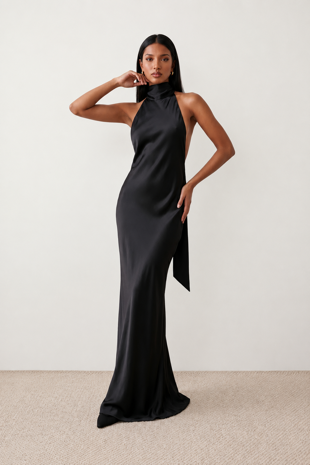 Woman wearing the Winnie satin halter maxi dress featuring a glossy satin finish, halter neckline with tie-back detail, open draped back, and a floor-length relaxed silhouette.