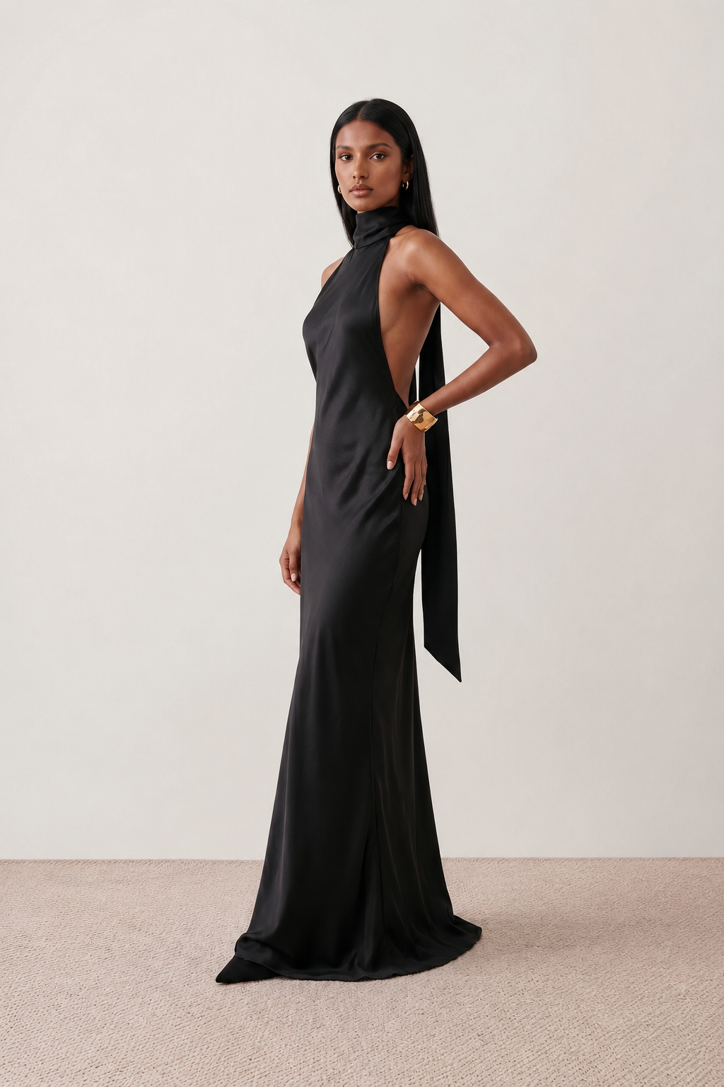 Woman wearing the Winnie satin halter maxi dress featuring a glossy satin finish, halter neckline with tie-back detail, open draped back, and a floor-length relaxed silhouette.