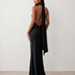Woman wearing the Winnie satin halter maxi dress featuring a glossy satin finish, halter neckline with tie-back detail, open draped back, and a floor-length relaxed silhouette.