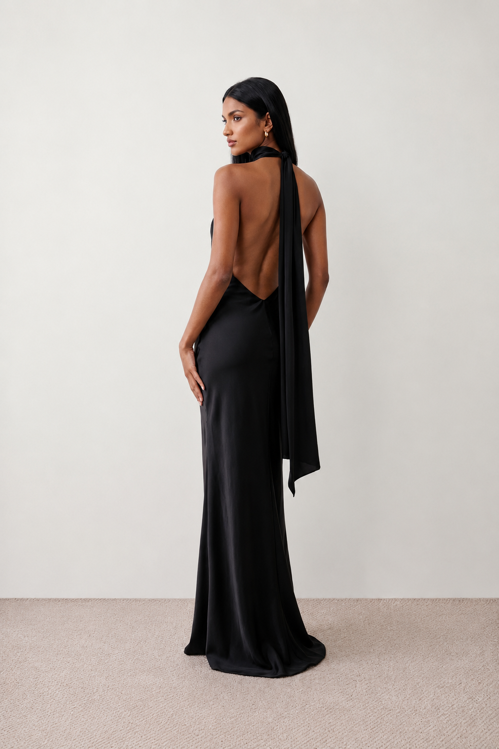 Woman wearing the Winnie satin halter maxi dress featuring a glossy satin finish, halter neckline with tie-back detail, open draped back, and a floor-length relaxed silhouette.